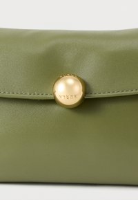 Zöld műbőr borítéktáska lekerekített aranyszínű patentzárral. Simatapintású és enyhe fényű felület. Varrt díszítéssel az élek mentén.