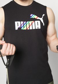 Débardeur de sport noir avec un logo "PUMA" rayé multicolore et un logo de chat. Tissu texturé, design simple avec col rond.
