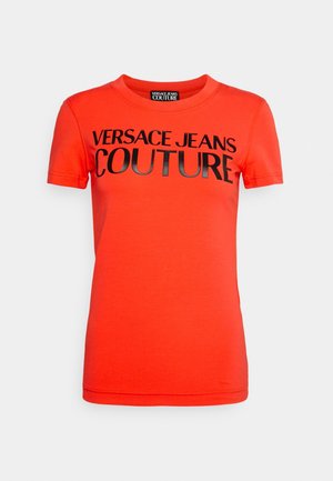 Červené bavlněné tričko s krátkými rukávy s velkým černým nápisem "VERSACE JEANS COUTURE" přes přední stranu. Hladká textura, klasický střih.