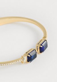 Zelta bangles ar divām lielām zilo dārgakmeņu akmeņu un mazām caurspīdīgām detaļām, ar gludu pulētu apdari un teksturētu joslu.