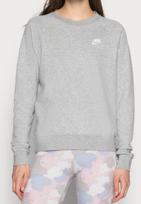 Felpa grigia con polsini e orlo a coste, con logo bianco Nike sul petto. Realizzata in morbido materiale testurizzato.