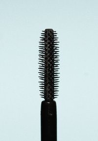 Rímel negro con un aplicador esbelto y alargado, que presenta cerdas cortas y densamente agrupadas dispuestas en un patrón en espiral.