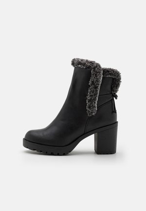 Schwarzer Knöchelstiefel mit klobigem Absatz, strukturierter Sohle und grauem Kunstfellbesatz am oberen Rand und Öffnung.