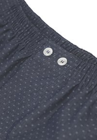 Mutande in tessuto blu scuro con un piccolo motivo a pois bianchi, vita elasticizzata e due bottoni bianchi nella zona del gancio.