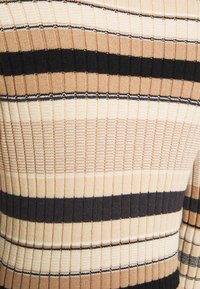 Maglione lavorato a maglia con una texture a coste verticali con strisce alternate in beige, crema e nero. Design aderente di peso medio.