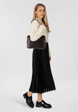 Brown leather handbag with a smooth texture, a front pocket, and a silver anchor accent. Paired with a cream sweater and black pleated skirt.