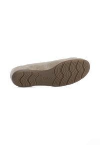 Beige suède platte schoen met een rubberen zool die een golvend loopvlakpatroon en een geperst merkteken heeft. Gladde textuur en ronde vorm.