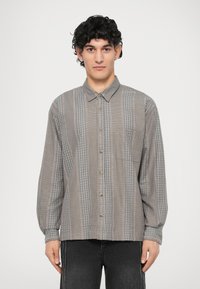 Camicia button-up grigia con motivo a quadri, caratterizzata da maniche lunghe, colletto e taschino sul petto. Texture morbida con dettagli sottili.