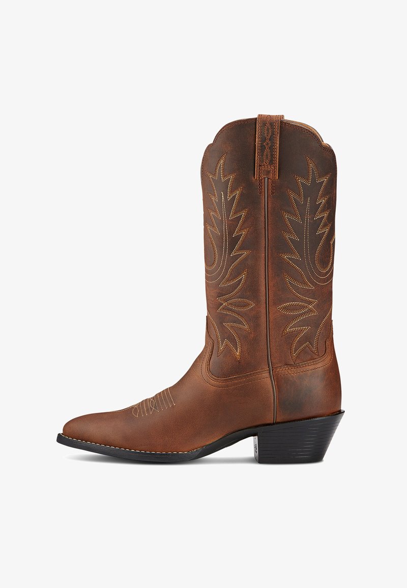 Botas de vaquero de cuero marrón con puntera afilada, costuras decorativas y sutiles patrones de hojas. Presentan un tacón bajo y asas reforzadas.
