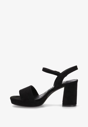 Sandalia de tacón de ante negra con un diseño de doble tira, punta abierta y tacón grueso. Hebilla ajustable en el tobillo con herrajes de metal.