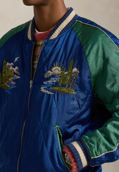 Modra satenasta bomber jakna z zelenimi poudarki, s vezenimi motivi gora in gozdov, z zadrgo in rebrastimi manšetami.