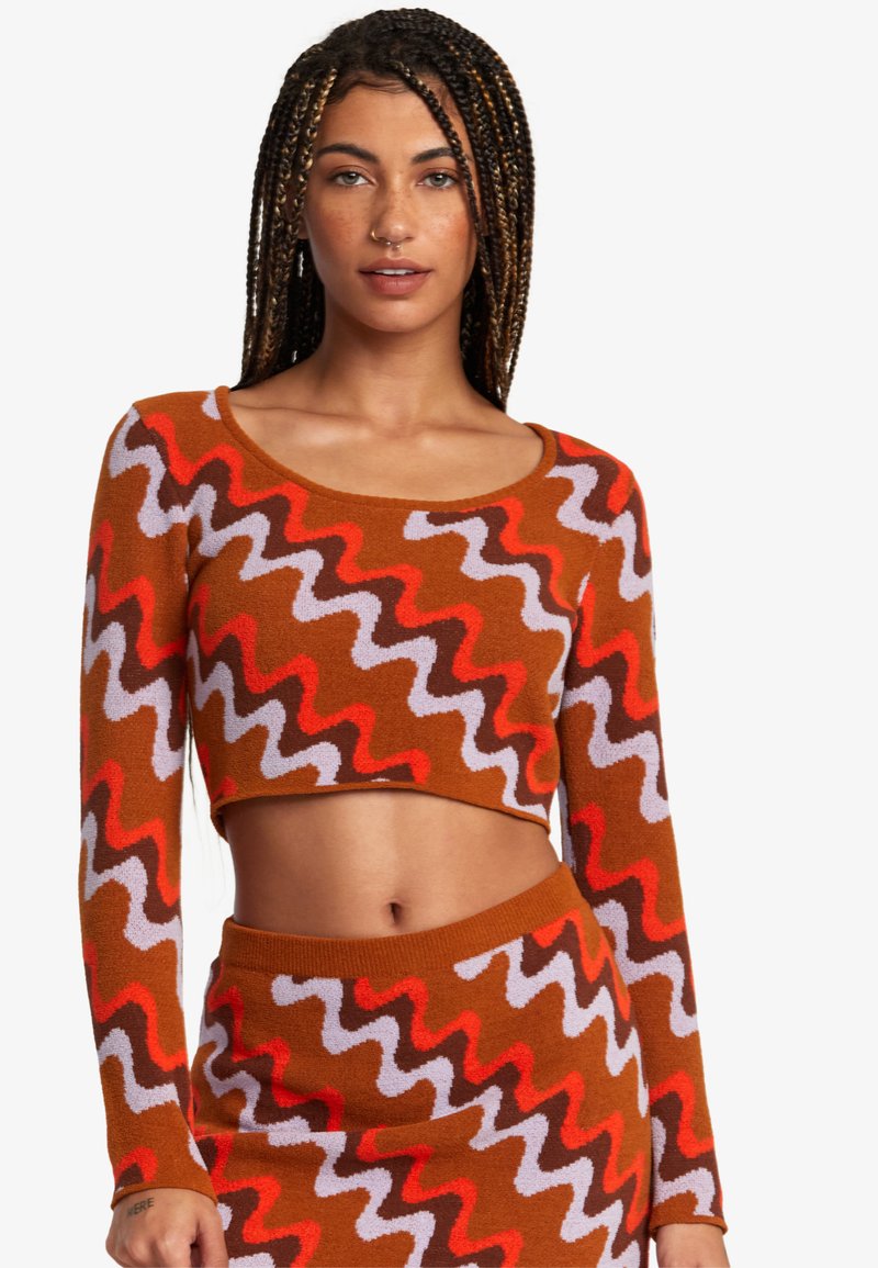 Brun strikket crop top med et zigzag mønster i rød, lilla og mørkebrun, med lange ærmer og en rund halsudskæring.