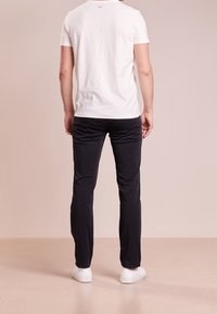 Vit bomull t-shirt, kortärmad, med rund halsringning. Kombinerad med mörkblå byxor och vita sneakers. Enkel, avslappnad outfit.