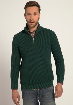 Suéter verde acanalado con un cuello de media cremallera, patrón de punto texturizado, mangas largas y una camisa de cuadros en capas visible en el cuello.