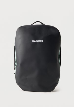 Čierny batoh Mammut s hladkým predným povrchom, horným držadlom a jemnými bočnými popruhmi na jednoduchom svetlom pozadí.