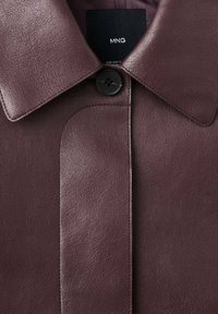 Bordowa skórzana kurtka z szerokim kołnierzem, pojedynczym czarnym guzikiem oraz gładką fakturą z widocznymi detalami szwów.