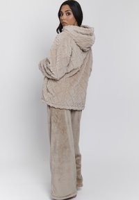 Beige, zachte hoodie met een gestructureerd patroon, voorzien van een capuchon en een relaxte pasvorm. Gecombineerd met bijpassende zachte, wijd-uitlopende broek.