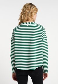 Camicetta a maniche lunghe a righe verdi e bianche con scollatura tonda e un piccolo bottone sul retro. Materiale in cotone morbido, vestibilità rilassata.