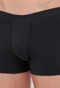 Fekete pamut boxer alsónadrág, sima textúrával, szoros illeszkedéssel, megerősített derékrésszel és elülső varrással.