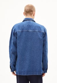 Blauwe spijkerjack met een relaxte pasvorm, voorzien van knoopmanchetten, een klassieke kraag en stikseldetails langs de naden.