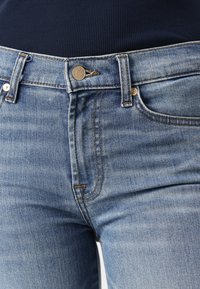 Light blue denim jeans with a classic five-pocket design, featuring a metal button closure and subtle fading throughout the fabric.
