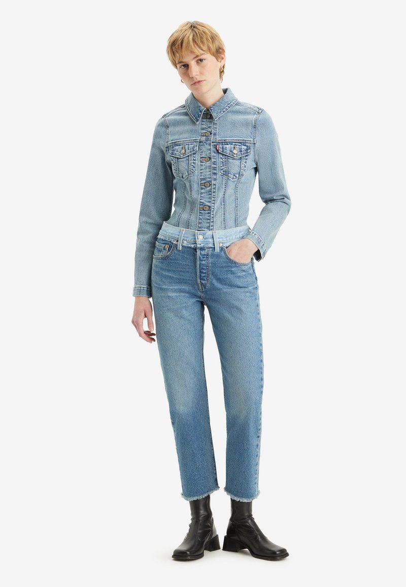 Lichtblauwe denimjas met een getailleerd ontwerp, voorzakken en een kraag, gecombineerd met bijpassende high-waisted jeans met rafelige zoom.