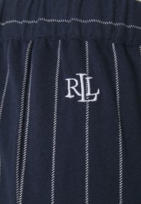 Mörkblå tygshorts med vita vertikala ränder. Elastisk midja med rynkad detalj. Vitt broderat "RL"-logotyp på framsidan.
