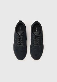 Baskets en mesh noir avec surface texturée, bout rond et design à lacets. Présentent un marquage subtil sur le côté et un intérieur rembourré.