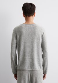 Szary dzianinowy top z długim rękawem, z okrągłym dekoltem, miękką teksturą i prostym wzorem. Posiada długie rękawy i prosty dół.