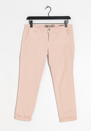 Světle růžové dámské kalhoty s vyšívanými květinovými detaily na kapsách, ohrnutými lemy, zapínáním na knoflíky, zavěšené na černém ramínku na bílém pozadí.