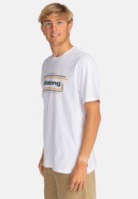 White cotton t-shirt featuring a graphic logo in green and orange shades, loose fit, short sleeves, and a crew neckline.