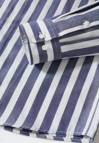 Camicia a righe con strisce alternate blu navy e bianche, realizzata in un tessuto liscio, con polsino abbottonato e colletto di tipo standard.
