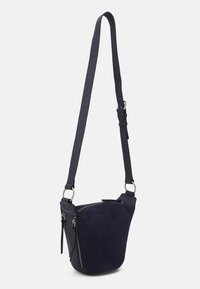 Sac bandoulière en suède bleu marine, de forme courbée, avec une sangle réglable et une poche zippée à l'avant. Il présente des garnitures en métal argenté et un matériau texturé.