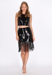 Fekete flitteres rövid felső és rojtos szoknya szett, fényes textúrával. Testhez simuló kialakítású, hasat mutató, pántos magassarkúval kiegészítve.