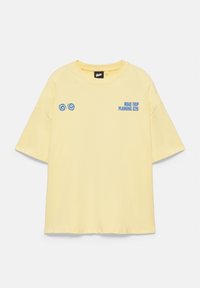 T-shirt jaune clair à manches courtes avec texte bleu "ROAD TRIP PLANNING S26" sur le côté gauche de la poitrine et deux motifs spirales bleus sur le côté droit de la poitrine.
