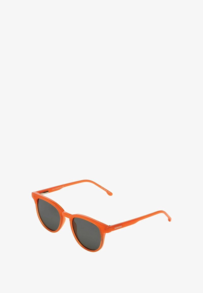 Lunettes de soleil en plastique orange avec une forme œil de chat, verres sombres et branches fines comportant un détail de logo sur la tempe.