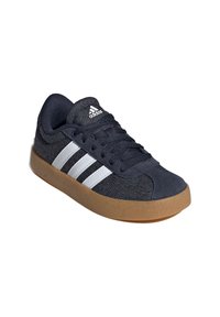 Dark blue canvas sneaker with three white stripes, round toe, padded collar, and gum rubber sole. Features textured fabric and lace-up design.