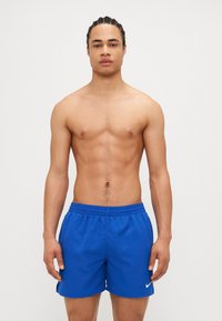 Blå Nike badebukser med elastisk talje og sidesømme. Glat, letvægtsstof. Ingen synlige mønstre eller hardware detaljer.