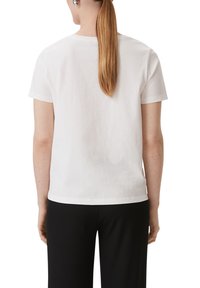 Weißes T-Shirt mit kurzen Ärmeln, geradem Schnitt, glatter Textur und Rundhalsausschnitt. Keine sichtbaren Muster; einfaches, sauberes Design.