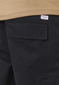 Shorts cargo noirs en tissu texturé, avec une poche arrière et une étiquette portant "JACK & JONES EST.1990" sur la ceinture.