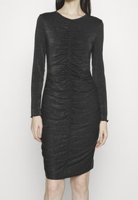 Svart långärmad klänning i glittrigt tyg, med rynkade detaljer fram och vid ärmarna för en figurnära silhuett.