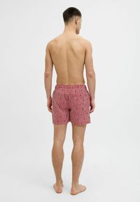 Bañador de rayas rojas y blancas con cintura ajustable y pequeños estampados. Diseñado para la comodidad y la movilidad.