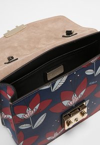 Kabelka s květinovým vzorem, navy modrým texturovaným exteriérem, zlatými doplňky a semišovým interiérem. Disponuje uzávěrem na sponu a vnitřním podšívkou.