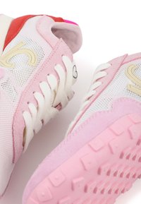 Helle rosa Mesh-Sneaker mit dunkleren rosa und roten Akzenten. Verfügt über dicke weiße Schnürsenkel, eine strukturierte Sohle und ein Herzmotiv an der Seite.