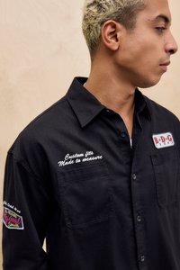 Fekete gombos ing két első zsebbel, hímzett részletekkel és gallérral. "Custom fits" és "B.D.G Jeans" márkajelzéssel.