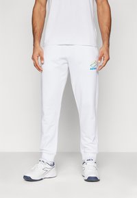 Weiße Jogginghosen mit einer lockeren Passform, ausgestattet mit einem gestickten Lotto-Logo in Blau und Grün. Mit Rippstrickbündchen und bequemem Material.