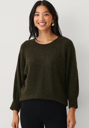 Donkergroene, gebreide trui met structuur, relaxed fit, ronde halslijn en lange, iets puffed mouwen. Glad accentdetail aanwezig.