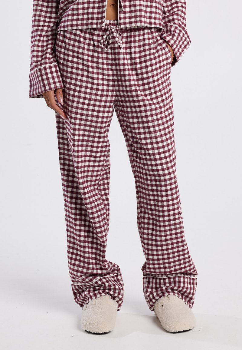 Tarkistettu pyjama-asuste burgundinpunaisena ja valkoisena. Pehmeä kangas, löysä istuvuus, joustava vyötärö, jossa on nyöri. Yhdistetty kermavärisiin pörröisiin tossuihin.