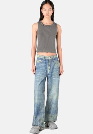 Grå ribbade linnepar med vida blå jeans i en ljus tvätt med subtila blekningar; grå skor fulländar outfiten.