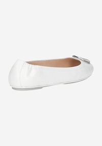 Chaussures plates blanches en cuir lisse, avec un bout arrondi et une boucle en argent décorative à l'avant, dotées de bords élastiques.